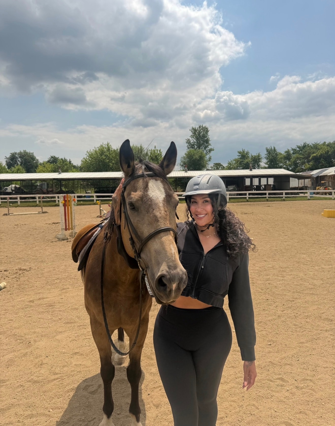Woman standing beside her horse at a riding arena